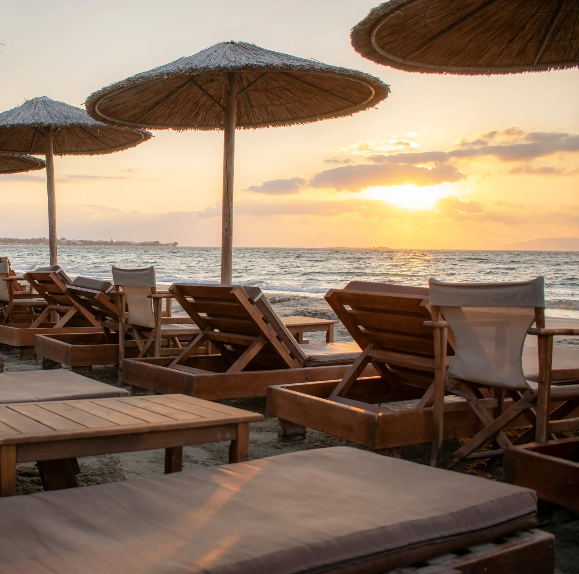 Καθιστικό παραλίας και ψάθινες ομπρέλες στο ηλιοβασίλεμα