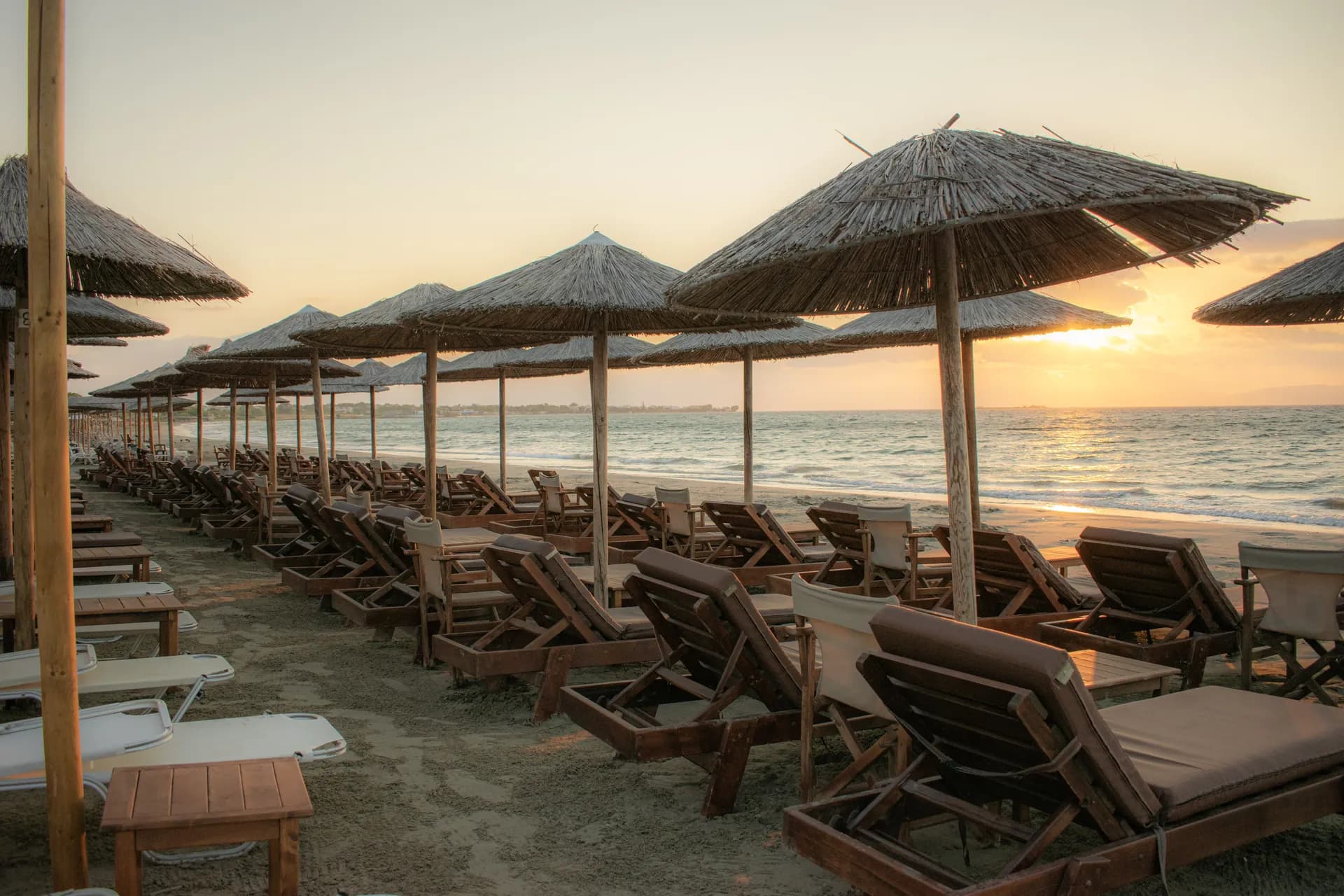 Ηλιοβασίλεμα πάνω από τις ψάθινες ομπρέλες και τις ξαπλώστρες