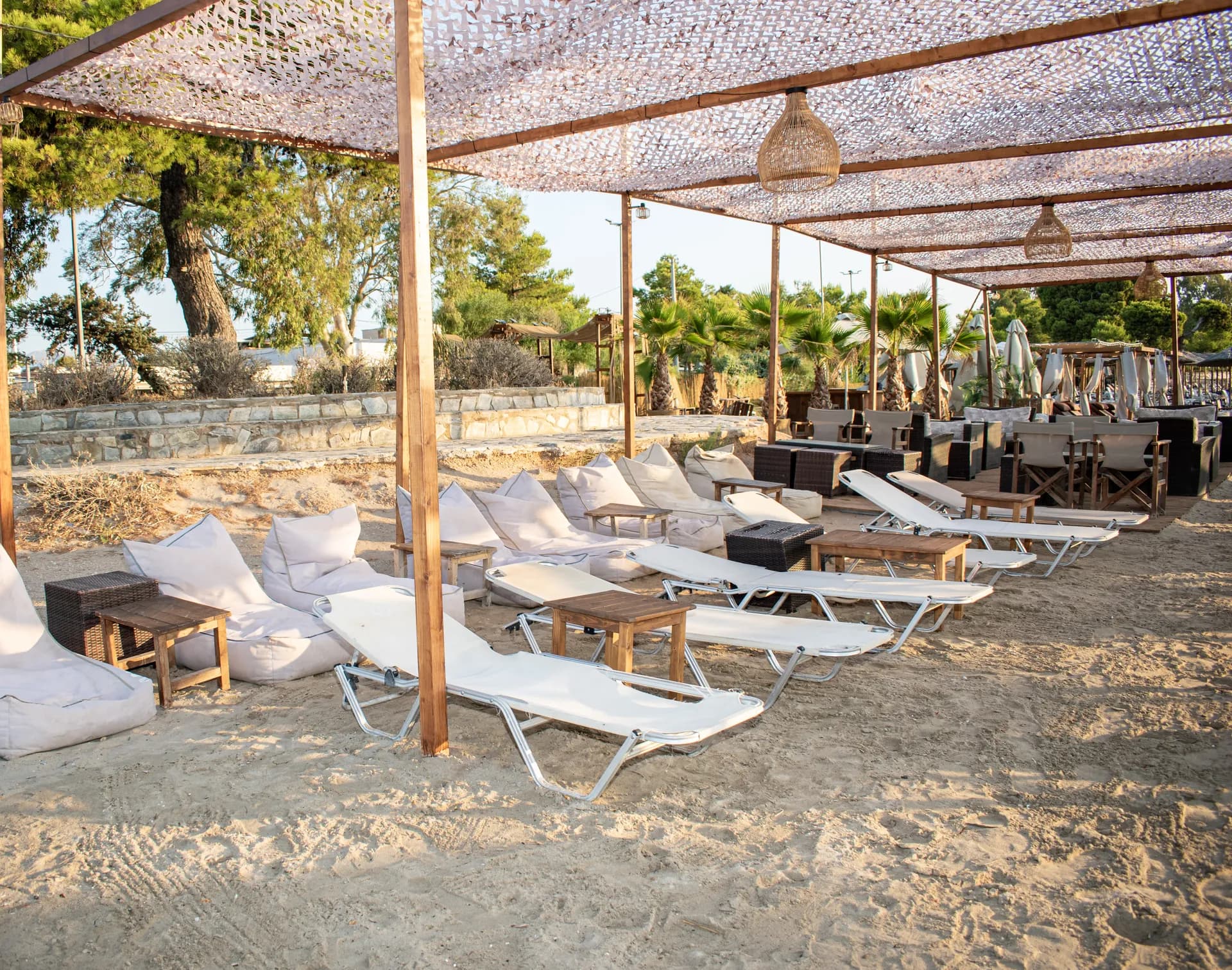 Λευκά κρεβάτια lounge και ψάθινες ομπρέλες στην παραλία